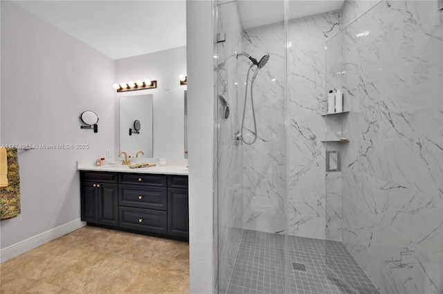 bathroom with baseboards, double vanity, a marble finish shower, and a sink