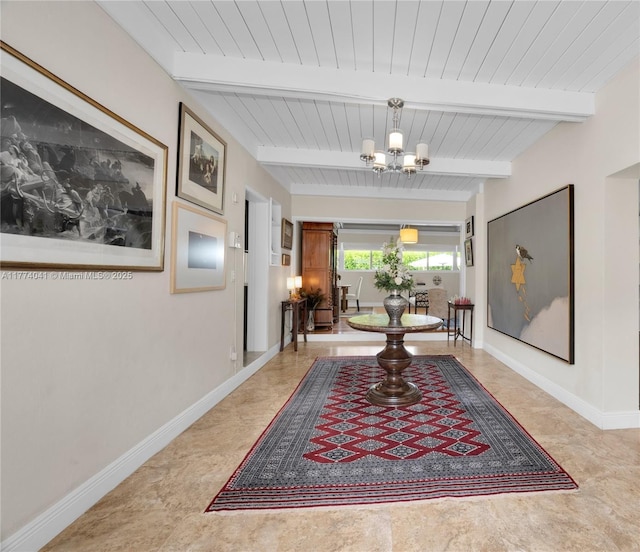hallway with baseboards, beamed ceiling, and a chandelier