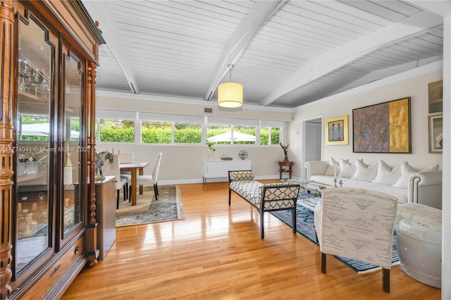 living room featuring baseboards, light wood finished floors, visible vents, and beam ceiling