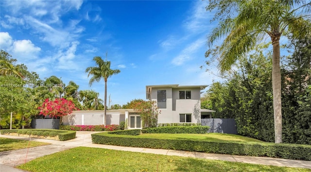view of front facade with a front yard, stucco siding, and fence