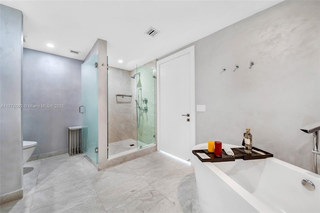 bathroom featuring a shower stall, toilet, a freestanding tub, marble finish floors, and recessed lighting