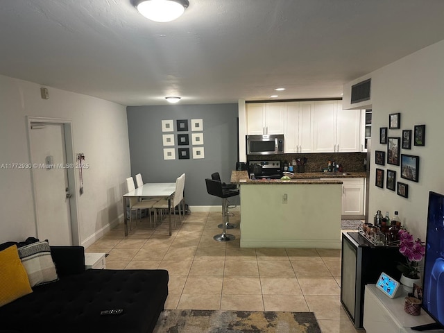 7951 SW 104th Unit 210D, Miami, FL 33156 - kitchen with stainless steel appliances, white cabinetry, backsplash, light tile patterned floors, and baseboards