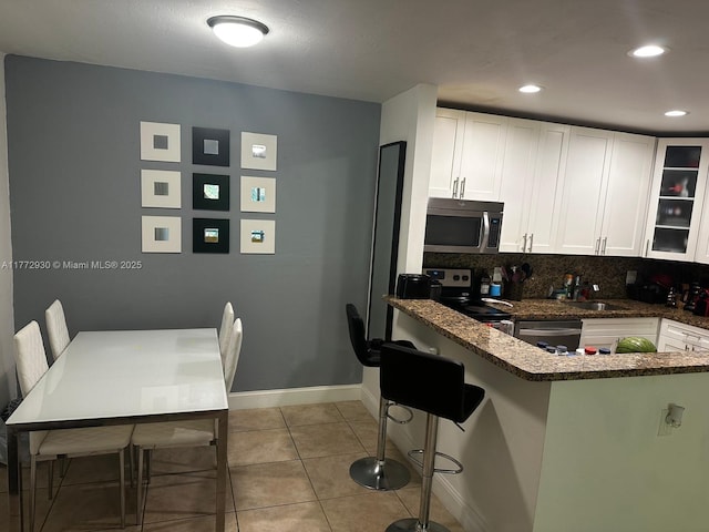 7951 SW 104th Unit 210D, Miami, FL 33156 - kitchen featuring appliances with stainless steel finishes, white cabinets, light tile patterned floors, decorative backsplash, and glass insert cabinets