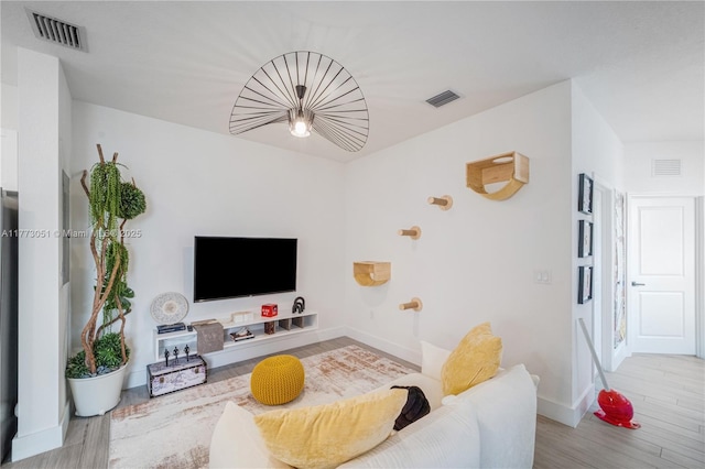 living area featuring baseboards, visible vents, and wood finished floors