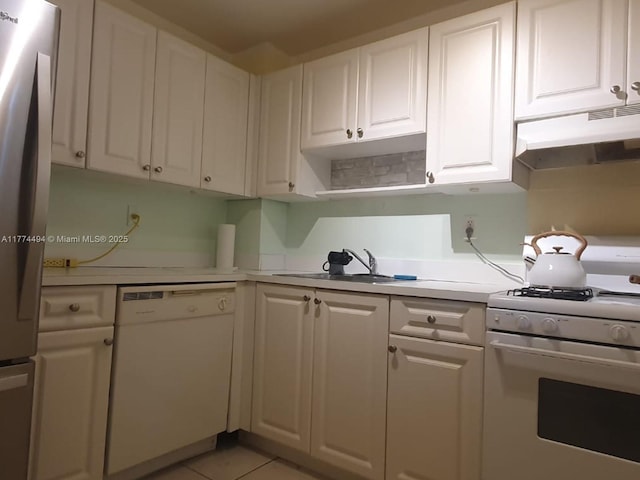 kitchen featuring white appliances, under cabinet range hood, a sink, light countertops, and white cabinets