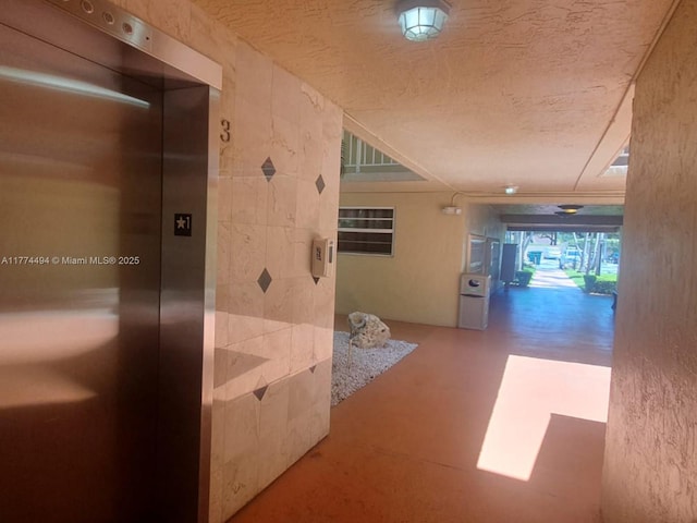 hallway featuring elevator and a textured ceiling