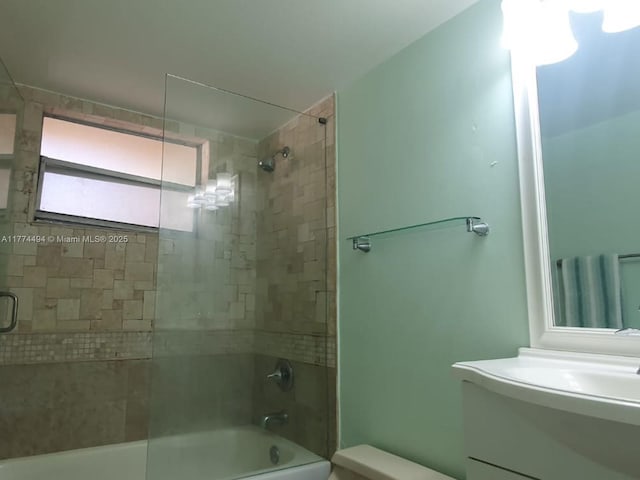 bathroom featuring toilet, combined bath / shower with glass door, and vanity