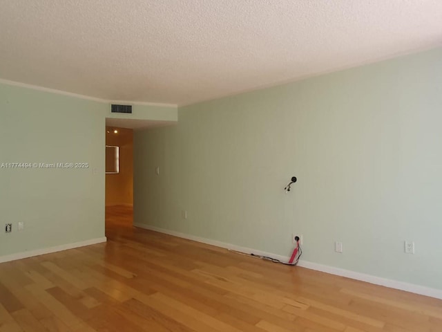 unfurnished room featuring a textured ceiling, wood finished floors, and baseboards