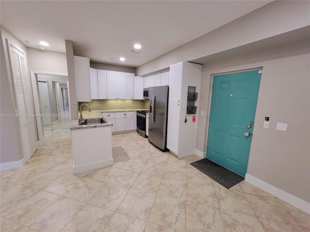kitchen with white cabinets, baseboards, a sink, light stone countertops, and stainless steel appliances
