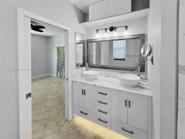 full bath featuring marble finish floor, double vanity, a sink, and a textured wall