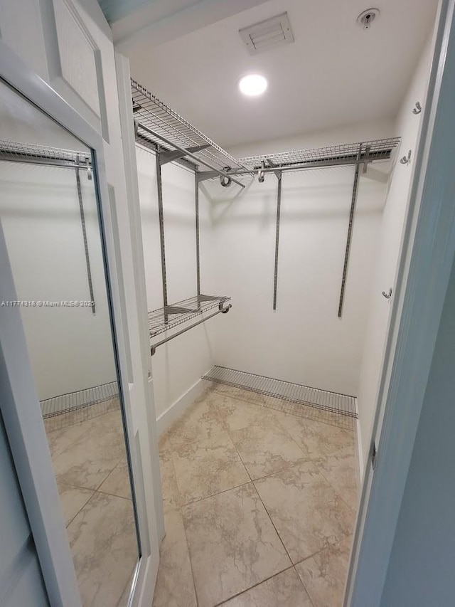 walk in closet with marble finish floor