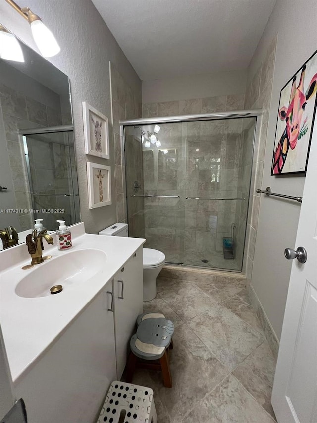 75 Gulfstream Rd Unit 211B, Dania Beach, FL 33004 - bathroom featuring a shower stall, vanity, a textured wall, toilet, and tile patterned flooring