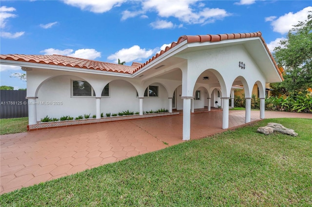 view of front facade with stucco siding, a tiled roof, and a front lawn