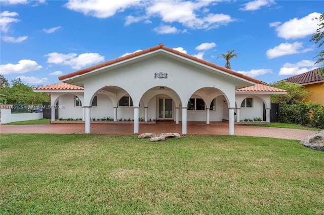 mediterranean / spanish home featuring a tiled roof, french doors, and a front lawn