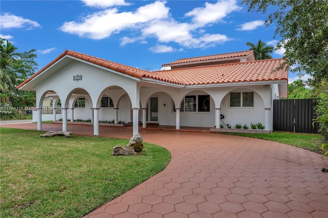view of front of home featuring a tile roof, stucco siding, a front lawn, and curved driveway