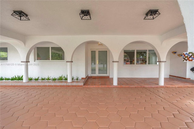 view of exterior entry featuring french doors, a patio, and stucco siding