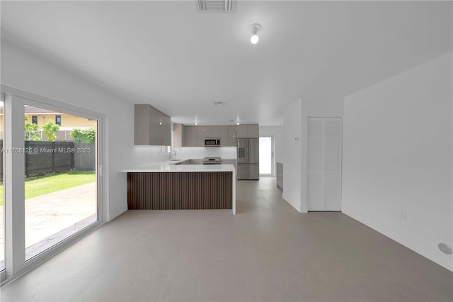kitchen featuring modern cabinets, a sink, light countertops, a peninsula, and stainless steel appliances