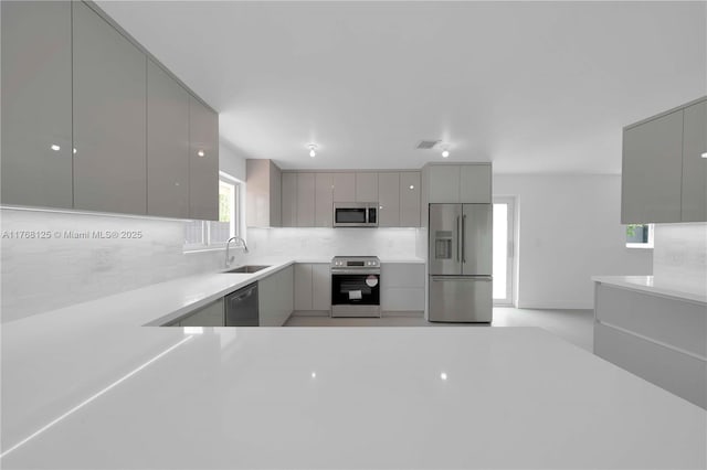 kitchen with tasteful backsplash, gray cabinetry, modern cabinets, appliances with stainless steel finishes, and a sink