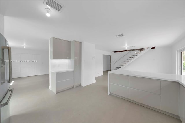 unfurnished room featuring concrete floors, stairway, and visible vents