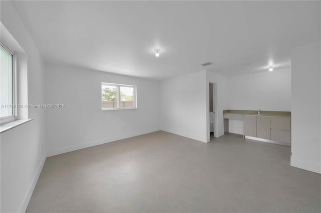 interior space featuring finished concrete flooring, baseboards, and visible vents