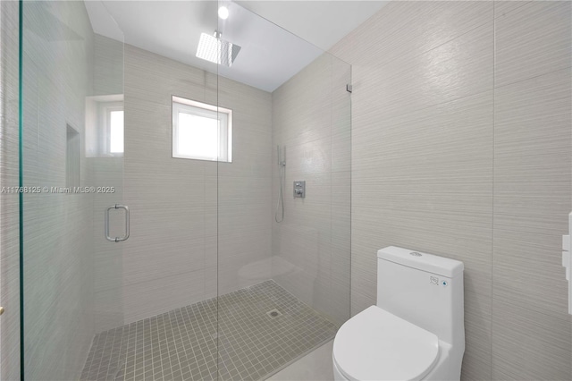 bathroom with a stall shower, tile walls, and toilet