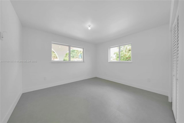 unfurnished bedroom with baseboards and finished concrete flooring