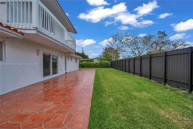 view of yard featuring a patio area, a fenced backyard, and a balcony