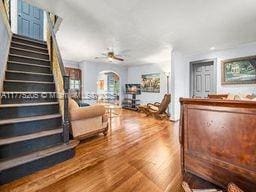 living area with wood finished floors, arched walkways, stairway, and ceiling fan