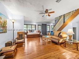 living area with a healthy amount of sunlight, stairway, and wood finished floors