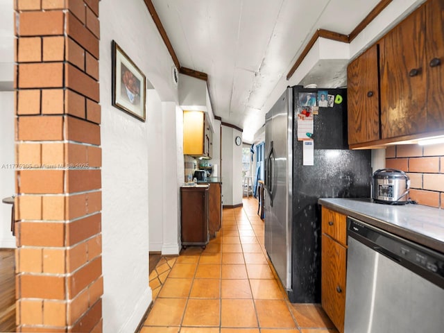 kitchen featuring light tile patterned flooring, stainless steel appliances, brown cabinetry, and tasteful backsplash