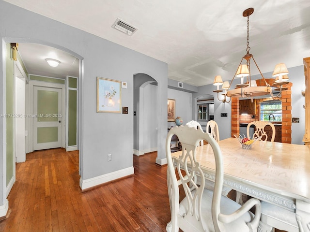 dining room with arched walkways, baseboards, visible vents, and hardwood / wood-style floors