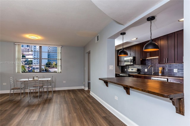 9180 W Bay Harbor Dr Unit 5C, Bay Harbor Islands, FL 33154 - kitchen featuring appliances with stainless steel finishes, butcher block counters, tasteful backsplash, dark wood-style floors, and a breakfast bar area