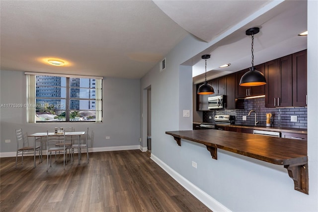 9180 W Bay Harbor Dr Unit 5C, Bay Harbor Islands, FL 33154 - kitchen featuring appliances with stainless steel finishes, wooden counters, backsplash, a breakfast bar area, and dark wood-style floors