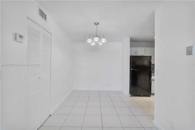 unfurnished dining area with baseboards, visible vents, light tile patterned floors, and an inviting chandelier