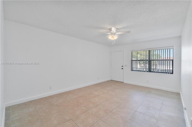 unfurnished room with baseboards, light tile patterned floors, a textured ceiling, and a ceiling fan