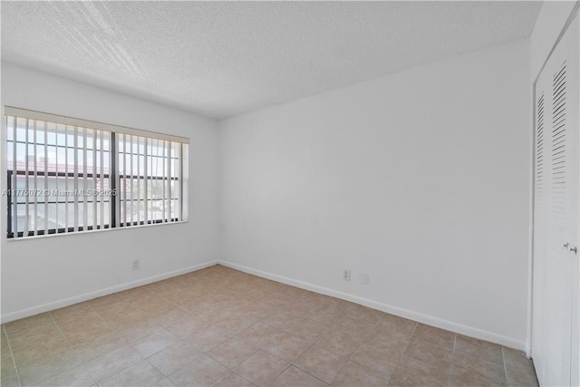 spare room featuring baseboards and a textured ceiling