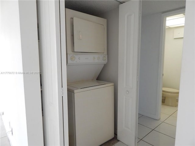 washroom with stacked washer / dryer, light tile patterned flooring, and laundry area