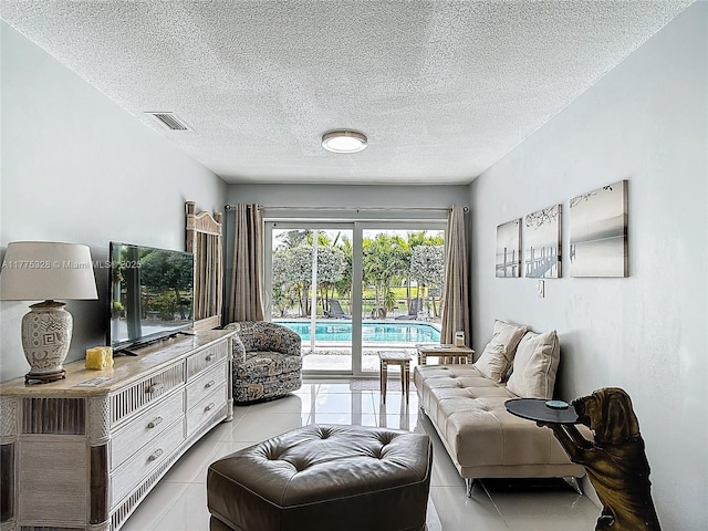 sitting room with a textured ceiling, visible vents, and light tile patterned floors
