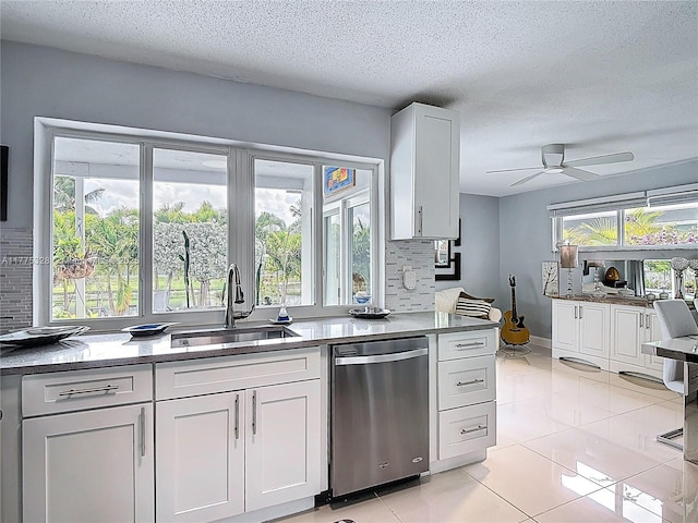 kitchen featuring decorative backsplash, a textured ceiling, white cabinetry, a sink, and dishwasher