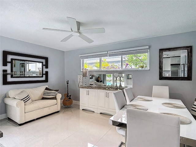 dining room featuring baseboards, a textured ceiling, ceiling fan, and light tile patterned flooring