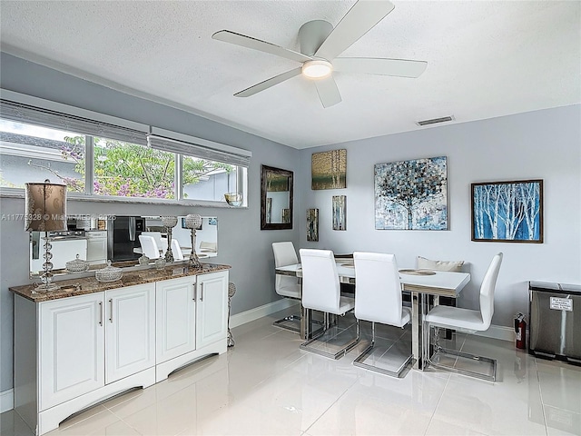 dining area with light tile patterned flooring, ceiling fan, a textured ceiling, baseboards, and visible vents