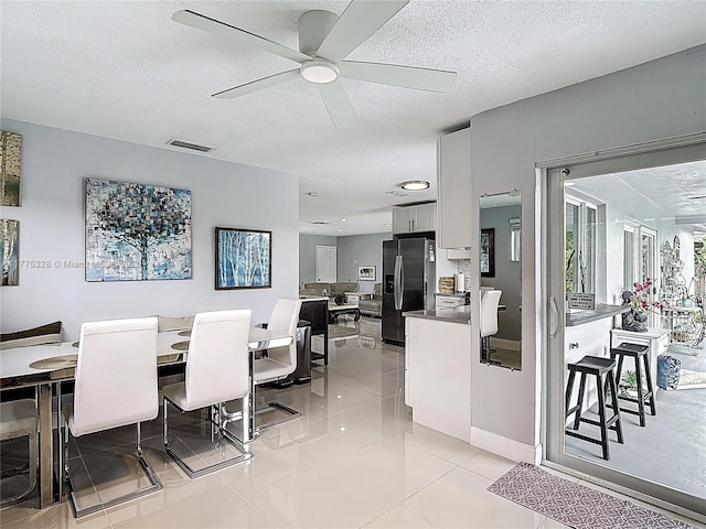 dining space featuring a textured ceiling, ceiling fan, visible vents, and light tile patterned floors
