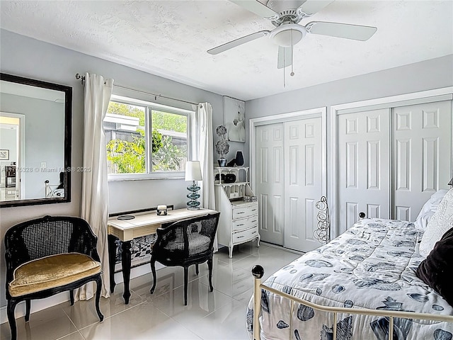 bedroom featuring light tile patterned floors, multiple closets, and a ceiling fan