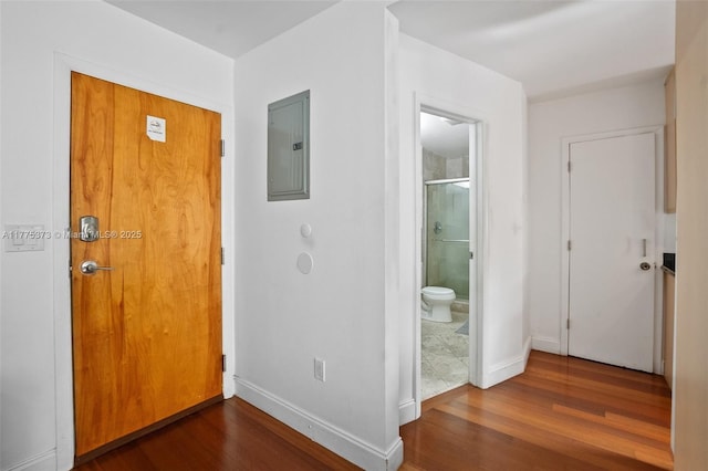 hallway with wood finished floors, baseboards, and electric panel