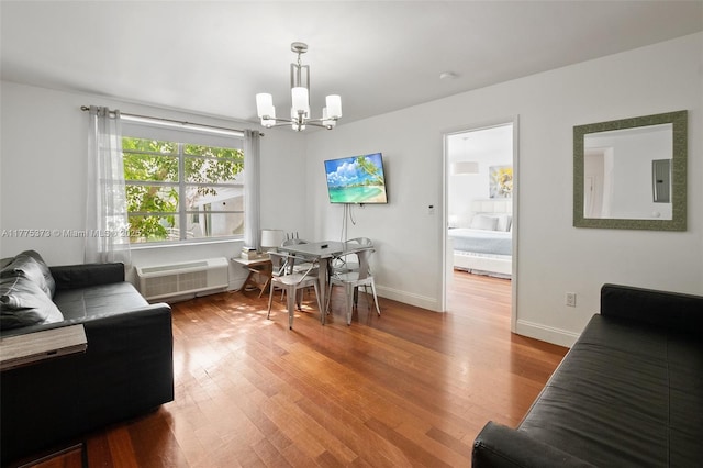 living area featuring a notable chandelier, baseboards, electric panel, a wall unit AC, and wood finished floors