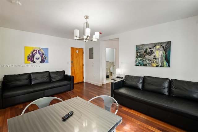 living area with baseboards, wood finished floors, a notable chandelier, and electric panel