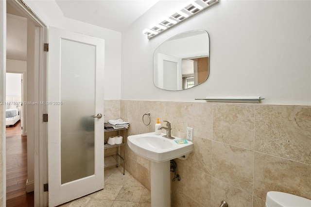 bathroom featuring toilet, a wainscoted wall, and tile walls