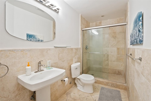 bathroom with a stall shower, tile patterned flooring, toilet, wainscoting, and tile walls