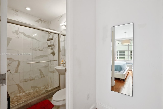 full bath with toilet, a stall shower, wood finished floors, and ensuite bath