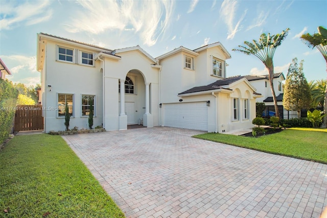 view of front of house featuring a front yard, a garage, decorative driveway, fence, and stucco siding